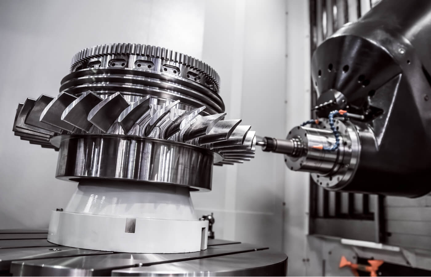 Das Bild zeigt eine komplexe CNC-Bearbeitung eines großen Zahnrad- oder Turbinenbauteils mit einem Fräskopf.