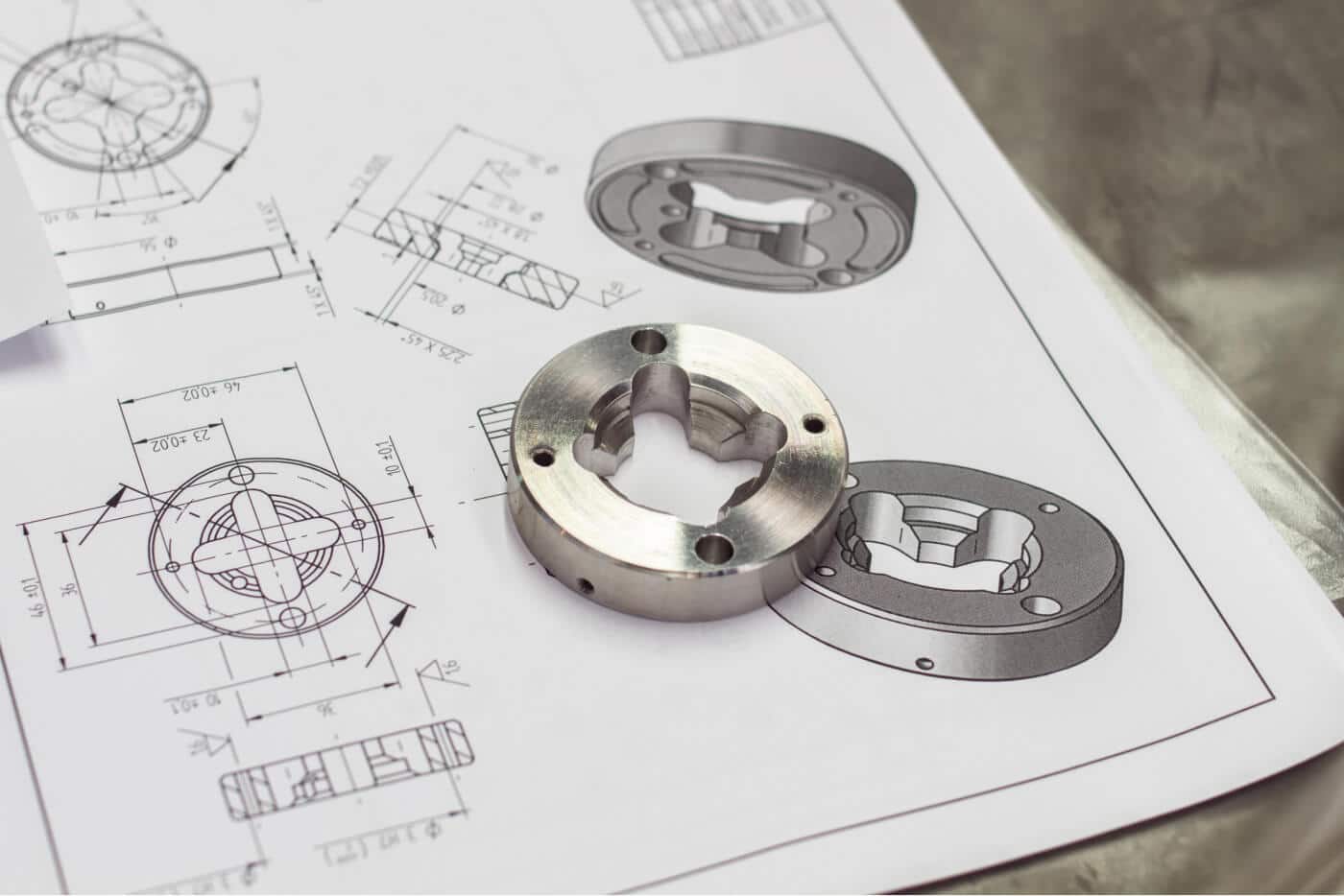 Das Bild zeigt technische Zeichnungen und ein gefertigtes Metallteil, was auf den Bereich CAD/CAM und Fertigung hinweist.