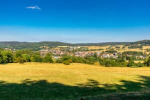 Das Bild zeigt eine typische Thüringer Landschaft mit Feldern und Wäldern.