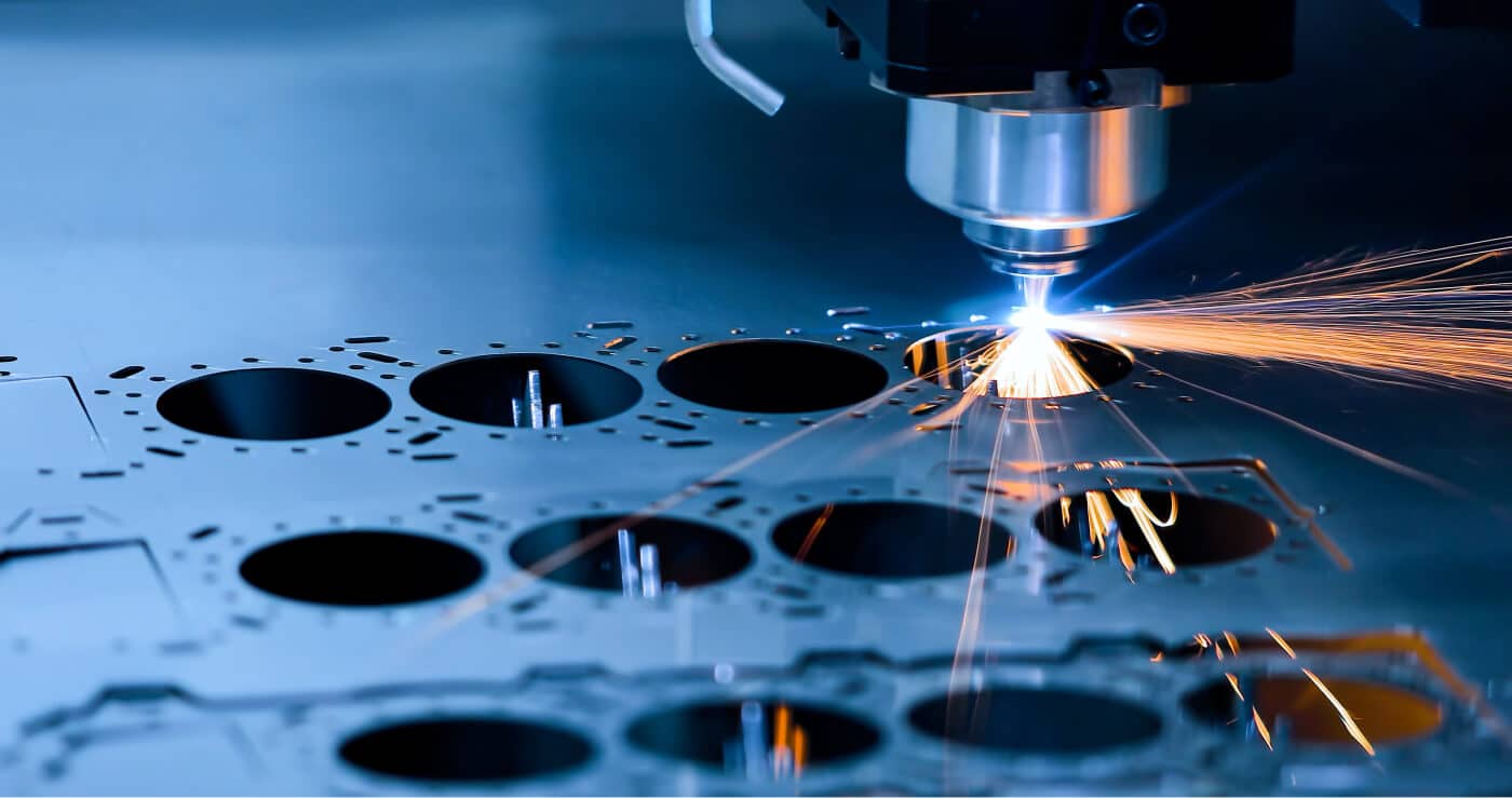 Das Bild zeigt einen Laser-Schneidprozess, bei dem ein Laserstrahl präzise Löcher in ein Metallblech schneidet, während Funken entstehen.